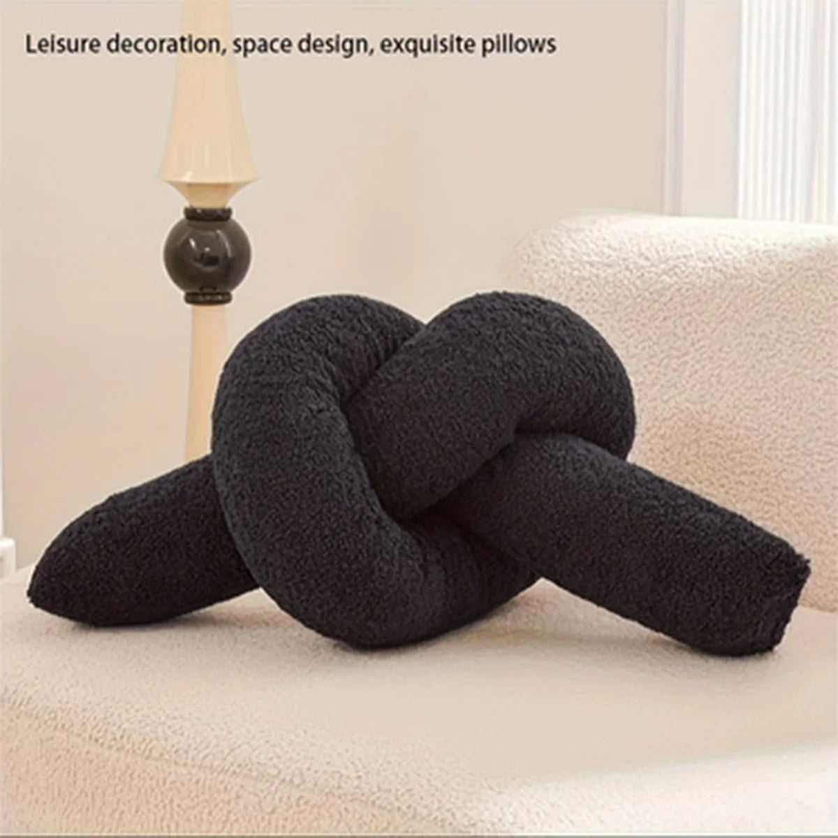Black knot-shaped pillow on a beige sofa with text about leisure decoration and space design.