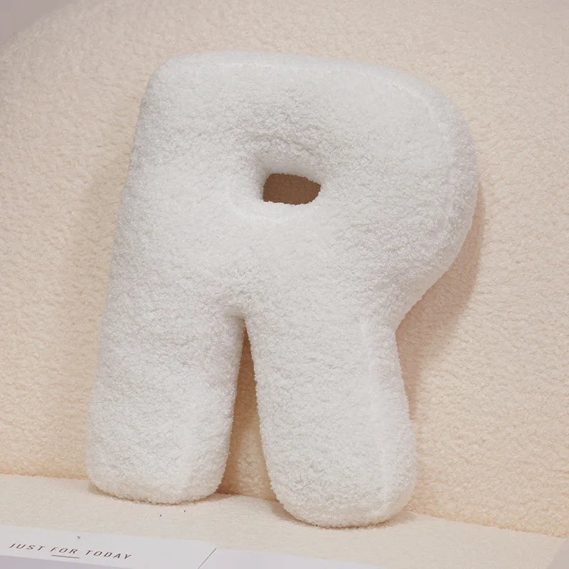 Letter 'R' shaped pillow on a soft beige background