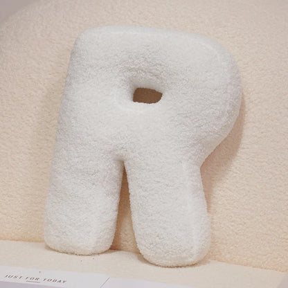Letter 'R' shaped pillow on a soft beige background