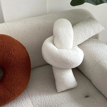 Decorative knot pillow on a sofa with other cushions.