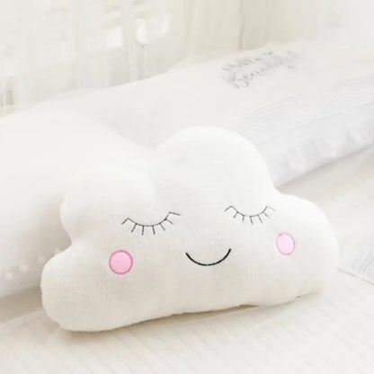 White cloud-shaped pillow with a smiley face on a light background
