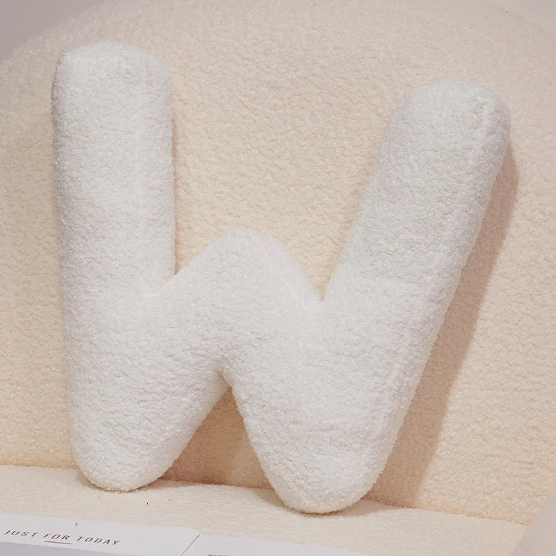 White letter 'W' pillow on a light pink background
