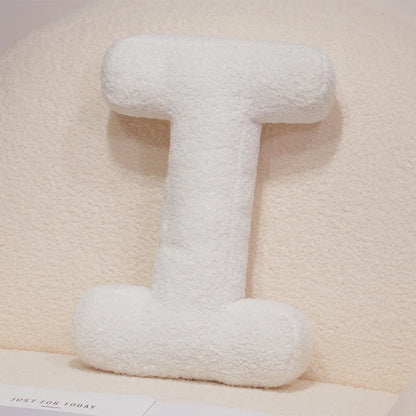 White fluffy letter 'I' pillow on a light beige background